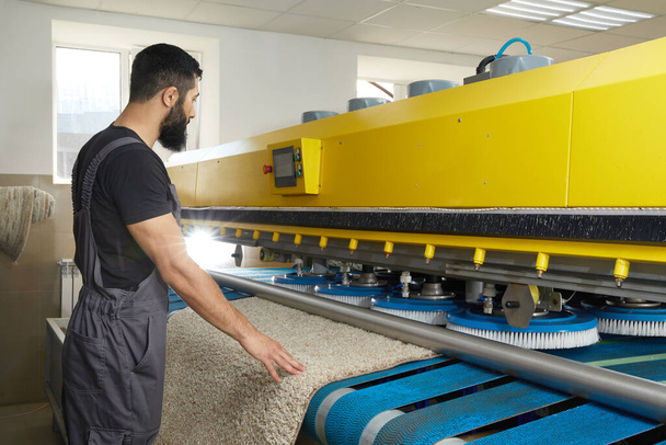 Mężczyzna działa dywan automatyczna pralka w profesjonalnej usługi pralniczej - Zdjęcie, obraz