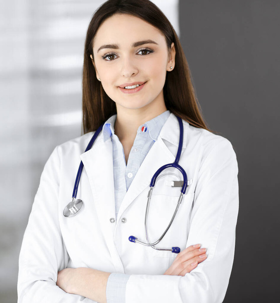 Smiling young woman-doctor is filling up medical recommendations using a clipboard. Therapist at work in a clinic office. Medicine concept - Foto, imagen