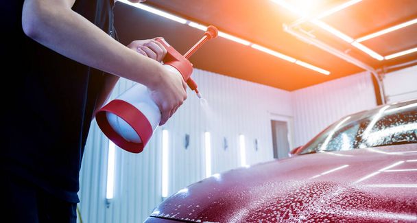 Worker washing car with active foam on a car wash. - Foto, afbeelding
