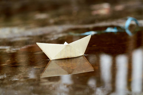 White paper boat floating in a puddle december - Foto, afbeelding