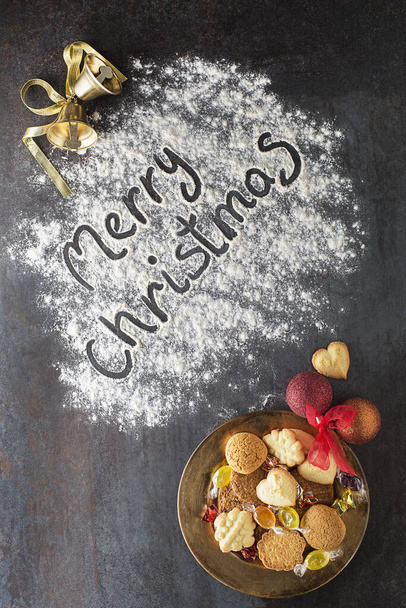 Merry Christmas text made with flour with decorations objects and cookies. Christmas, winter, new year concept background. - 写真・画像