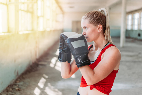 Indoors portrait of young, fit female boxer. Sport, active lifestyle. Copy space - Фото, изображение