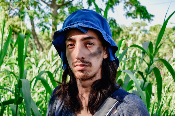 Fiatal hipszter farmer néz a kamerába a kertben. - Fotó, kép