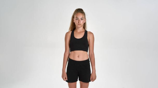 Portrait of cute sportive girl child in sportswear looking at camera, while posing isolated over white background - Foto, afbeelding