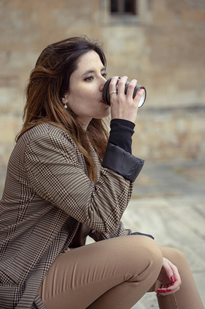 girl drinking a coffee on street and smiling - Zdjęcie, obraz