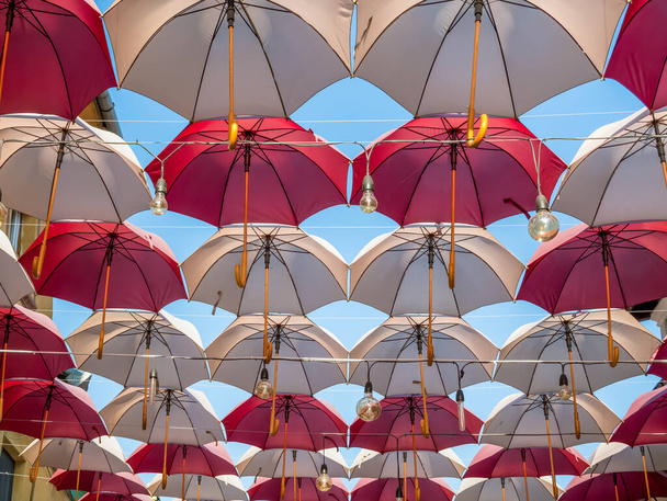 Αιωρούμενες έγχρωμες ομπρέλες και λαμπτήρες κατά του γαλάζιου ουρανού. - Φωτογραφία, εικόνα
