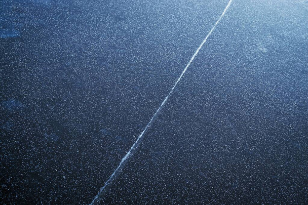 Abstract texture of dark ice with snow crystals and white line on the surface. Frozen river - Photo, Image