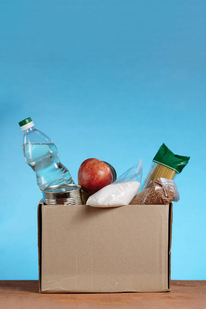 Κουτί δωρεάς με τρόφιμα που απομονώνονται σε λευκό φόντο. Κοντινό πλάνο διαφορετικών τροφίμων σε ένα κουτί εθελοντών. Donate Box, δωρεά και φιλανθρωπία έννοια. Κάθετη βολή - Φωτογραφία, εικόνα