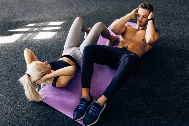 Sportive couple, woman and man train together, do exercises on the press in the gym, sport, fitness - Photo, Image