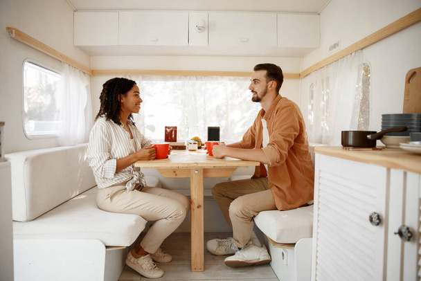 Love couple having breakfast in rv, camping in a trailer. Man and woman travels on van, romantic vacations on motorhome, campers leisures in camping-car - Zdjęcie, obraz