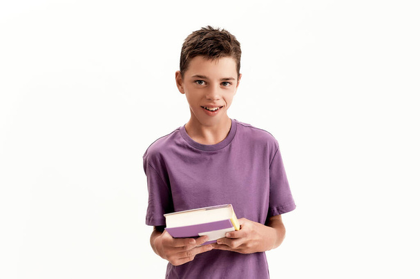 Portrait of teenaged disabled boy with cerebral palsy looking at camera and holding a book, posing isolated over white background - Fotografie, Obrázek