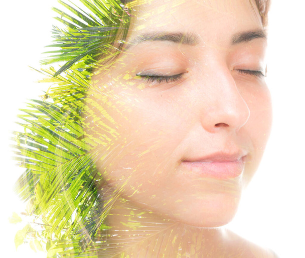 A double exposure portrait of a beautiful brunette with her eyes closed and palm tree leaves against white background - Foto, imagen