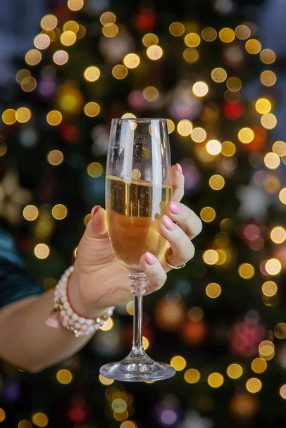 Champagne in mano sullo sfondo dell'albero di Natale. Concentrazione selettiva. Vacanze. - Foto, immagini