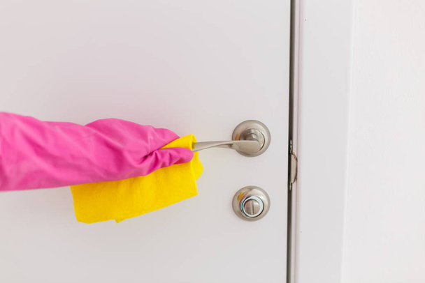 Mulher mão em luvas de borracha protetora segurando microfibra maçaneta da porta de limpeza, fazer a limpeza e desinfecção para uma boa higiene - Foto, Imagem
