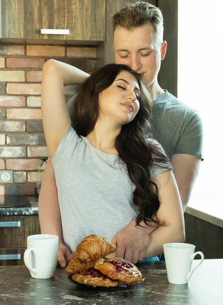 Young beautiful couple have breakfast in the early morning at home, hug, smile. - Foto, Bild