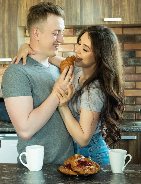 Young beautiful couple have breakfast in the early morning at home, hug, smile. - Valokuva, kuva
