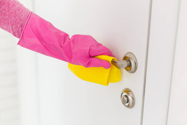 Mulher mão em luvas de borracha protetora segurando microfibra maçaneta da porta de limpeza, fazer a limpeza e desinfecção para uma boa higiene - Foto, Imagem