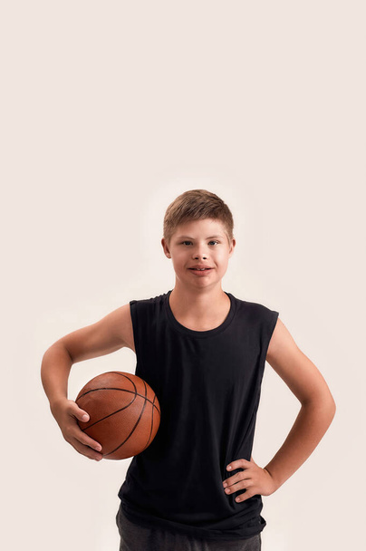 Portrait of cheerful disabled boy with Down syndrome looking at camera while posing with basketball isolated over white background - Foto, Bild