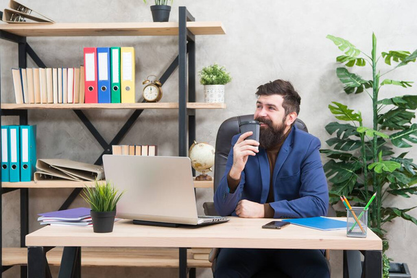 Behind every sucessful man is substantial amount of coffee. Bearded man drink coffee at work desk. Morning habit. Working in modern office. Workplace environment. Business lifestyle - Foto, Imagen