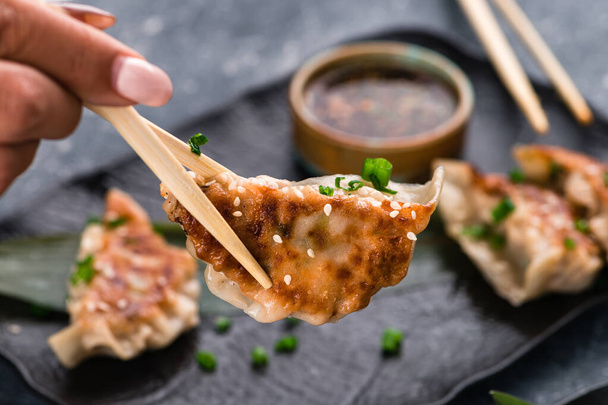 Traditional asian pan fried gyoza dumplings with a dip sauce, japaneese gyoza dumplings with meat and mushrooms on stick - Φωτογραφία, εικόνα