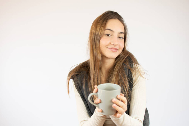 Portrét fotografie pěkné roztomilé dívky držící šálek kávy ukazuje v prázdném prostoru s úsměvem izolované na bílém pozadí - Fotografie, Obrázek