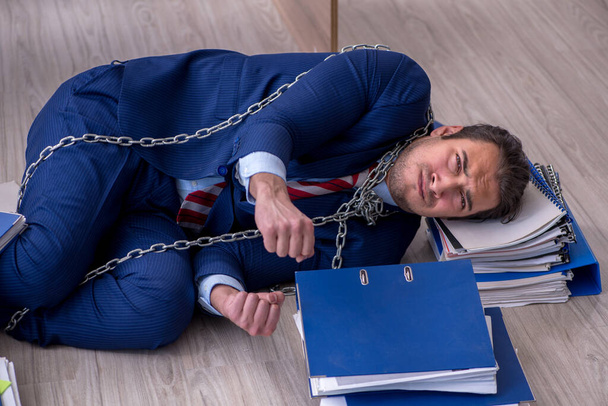 Прикованный к цепи мужчина недоволен чрезмерной работой в офисе - Фото, изображение