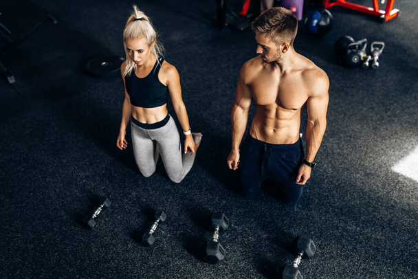 Attractive athletic people, man and woman working out with dumbbells in the gym - Foto, Imagem