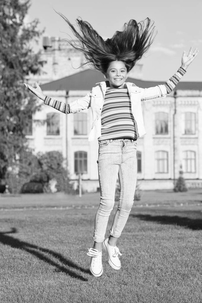 being carefree. full of energy. activity for kids. happy kid jumping and feel free. childhood happiness. small girl with curly hair jump outdoor. spring holiday celebration. child fly in motion - Foto, imagen