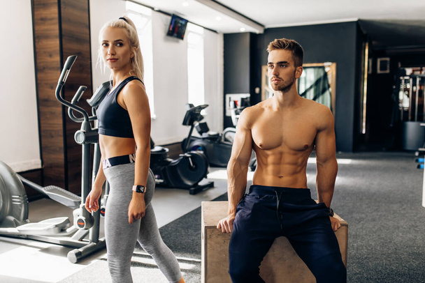 Sporty young couple, woman and muscular man, in sportswear in the gym - Foto, immagini