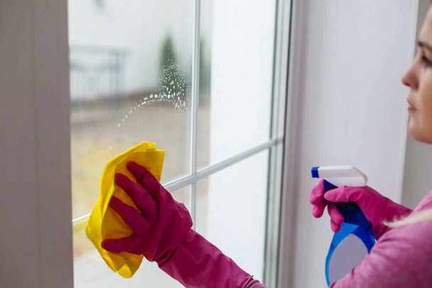 Donna che pulisce una finestra con un panno giallo - Foto, immagini