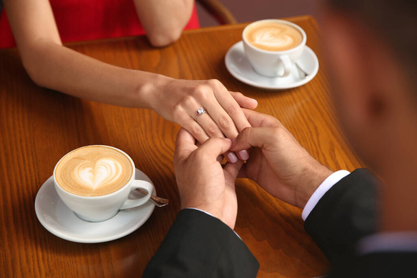 Man with engagement ring making proposal to his girlfriend in cafe, closeup - Zdjęcie, obraz