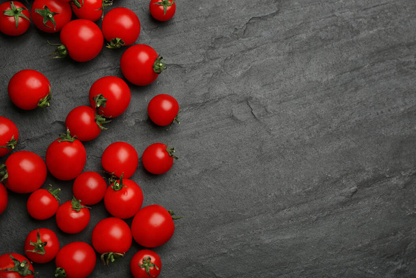 Fresh ripe cherry tomatoes on black table, flat lay. Space for text - Fotografie, Obrázek
