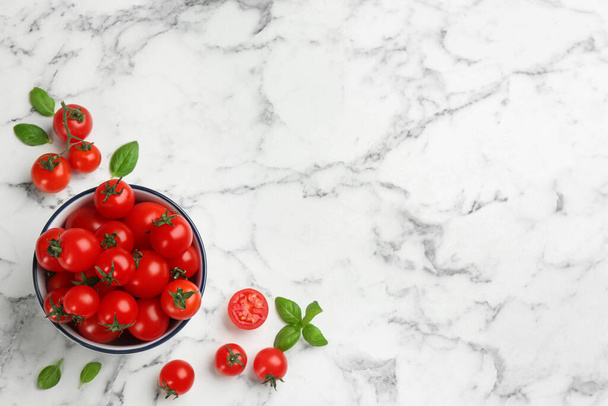 Flat lay composition with fresh cherry tomatoes and basil leaves on white marble table. Space for text - Foto, afbeelding