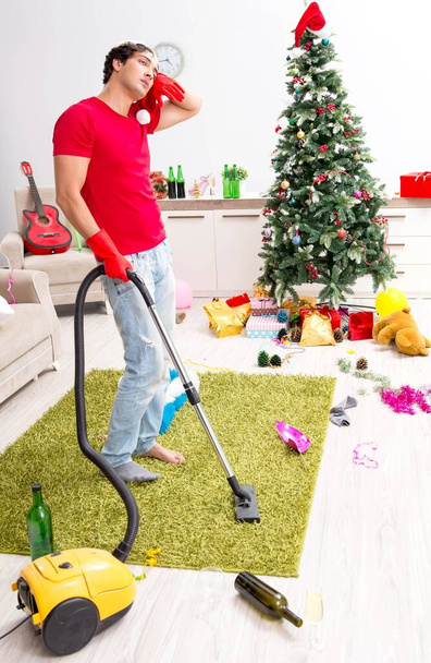 Καθαρίζει το διαμέρισμά του μετά τα Χριστούγεννα. - Φωτογραφία, εικόνα