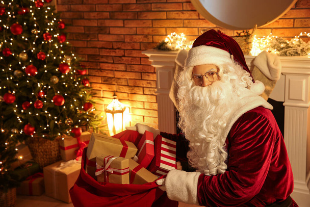 Santa Claus with sack of gifts in festively decorated room - Foto, immagini