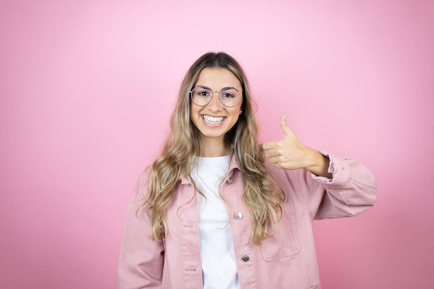 Young beautiful blonde woman with long hair standing over pink background smiling and doing the ok signal with her thumbs - Photo, Image