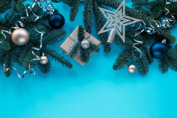 Fir branches, gift in a box and baubles on blue background. Christmas concept. Top view, flat lay, copy space. - Photo, image