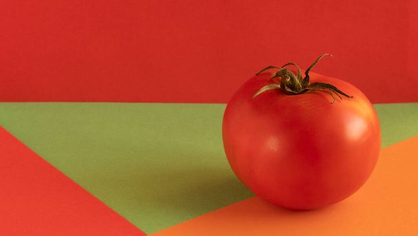 rote Tomate mit grünem Stiel, auf rotem Hintergrund, auf orangefarbenem Hintergrund, auf grünem Hintergrund, Konzept, Kopierraum - Foto, Bild