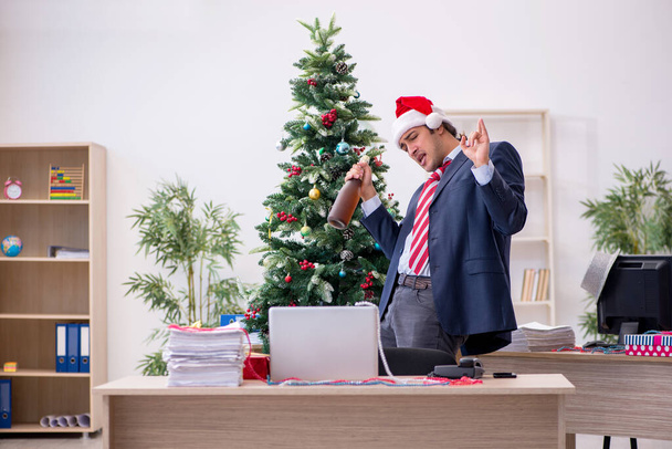 Молодой работник-мужчина празднует новый год в офисе - Фото, изображение