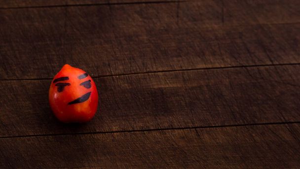 Een paar tomaten met grappige gezichten. Het concept van een gezonde voeding en levensstijl. Geïsoleerd op een houten achtergrond. - Foto, afbeelding
