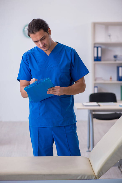 Νεαρός άνδρας γιατρός κρατάει σημειώσεις στο νοσοκομείο - Φωτογραφία, εικόνα