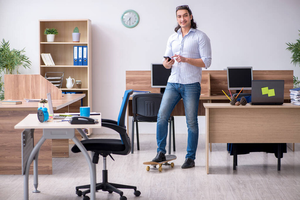 Young male employee with skateboard in the office - Foto, Bild