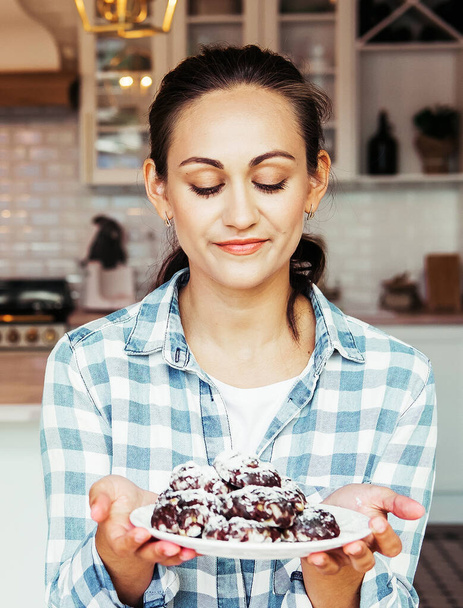 Egy gyönyörű fiatal nő, aki csokis sütit tart a kezében.. - Fotó, kép