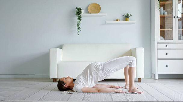 Pretty pregnant lady does exercises practicing yoga at home - Photo, Image