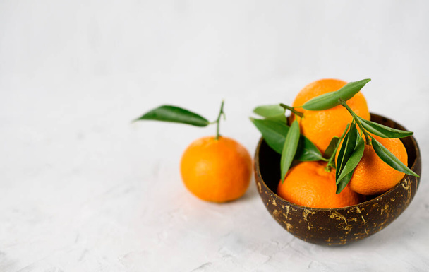 Schale mit frischen Zitrusfrüchten auf grauem Hintergrund. Mandarinen, Limetten und in Scheiben geschnittene Orangen mit Blättern auf dem Tisch. Seitenansicht. Ernährung und vegetarisches Konzept. - Foto, Bild