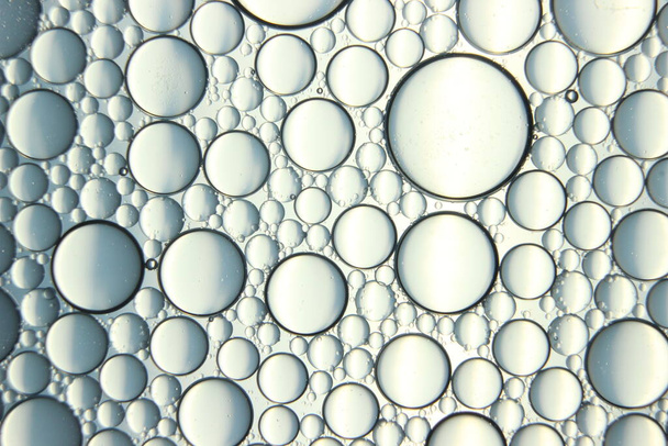 αφηρημένο υπόβαθρο μακροεντολή των κύκλων πετρελαίου που επιπλέουν πάνω από την επιφάνεια του νερού. Μακροσκοπική κοντινή άποψη των φυσαλίδων στο νερό. φυσαλίδες λαδιού στο μακροφωτογραφικό φόντο νερού - Φωτογραφία, εικόνα