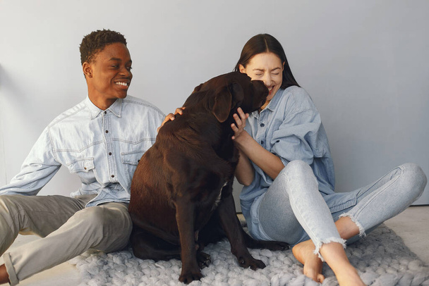 International couple on a blue background with a dog - Φωτογραφία, εικόνα