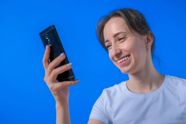 Женщина улыбается и использует смартфон, имеет видео-чат, интервью, консультации - Фото, изображение