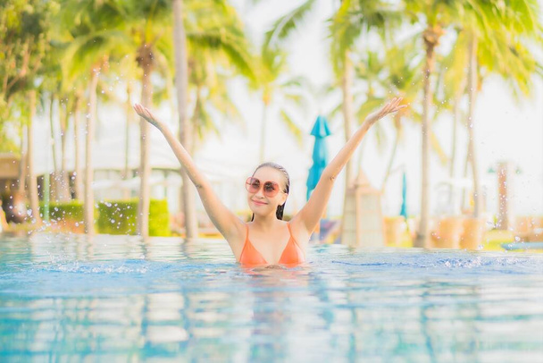 Retrato bonito jovem asiático mulher relaxar sorriso lazer ao redor piscina ao ar livre quase mar praia oceano no por do sol tempo para férias - Foto, Imagem