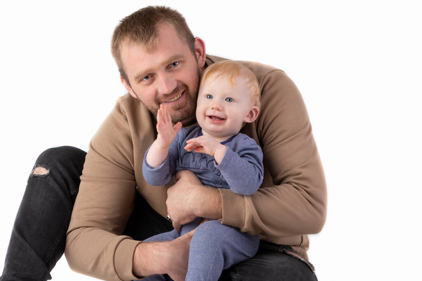 Over white background happy dad with one-year-old toddler smiling and looking at the camera. - Fotó, kép